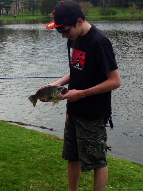A student holding a fish he caught in the pond on the SUNY New Paltz campus. Photo by Emily Demirjian