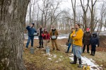 Creek Iverson, manager of the Brook Farm Project, New Paltz NY, gives an in depth explanation to the group of volunteers about the process of making maple syrup beginning with how to know a tree is a sugar maple, how large a tree must be to be tapped, and how much maple syrup each tree will make. Iverson explains that it takes approximately 10 gallons of sap to get just 1 quart of maple syrup. Photo by Dawna M. Cservak.