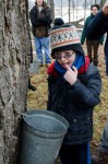 The first to be daring, volunteer Lucas Lemos dips his finger into the sap so that he may get his first taste of sap directly from a sugar maple tree at the Maple Sugaring Prep Work Party and Potluck taking place at the Brook Farm Project in New Paltz, NY. Photo by Dawna M. Cservak.