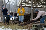Led by Creek Iverson, manager of the Brook Farm Project (second from the right), the group of volunteers participate in a sing a long to a customary lumberjack song, while Zack Baker of NYC, cuts the wood for the fire. Photo by Dawna M. Cservak.